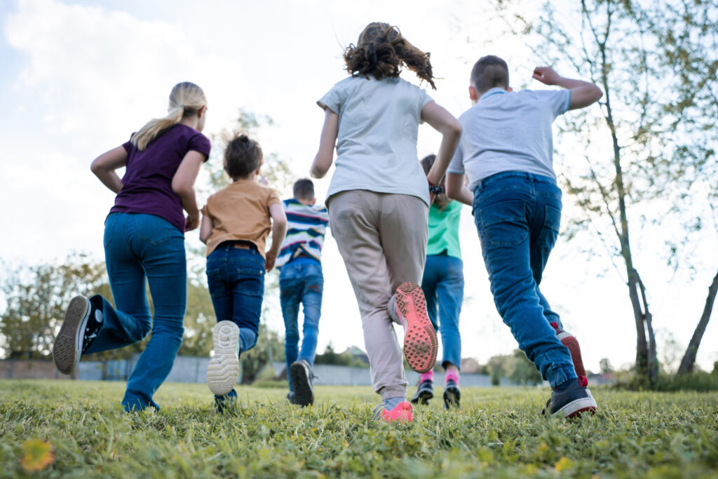 Kinder und Jugendliche rennen auf einem Rasenspielplatz