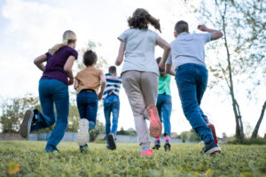 Kinder und Jugendliche rennen auf einem Rasenspielplatz